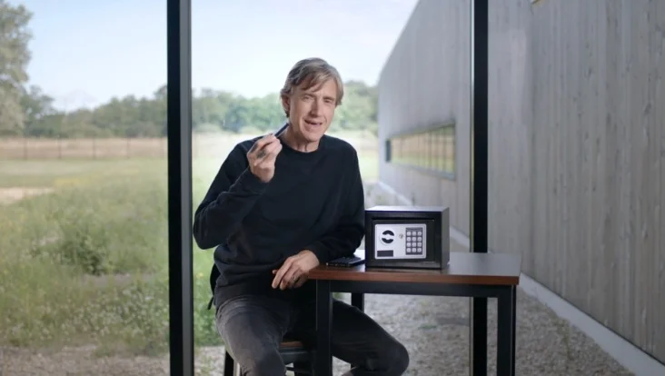 Ian Rogers holding a Ledger device, possibly gesturing to its small size or security.