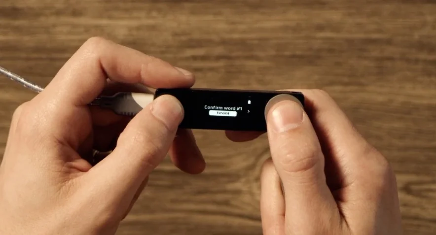 The Ledger Nano X screen requesting the user to 'Confirm word #1'.